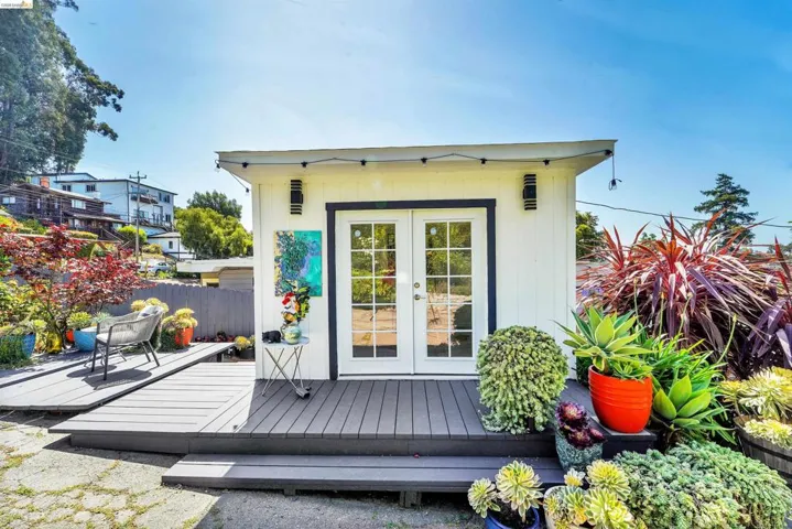 Detached auxiliary building with white siding, dual French doors, and dark trim