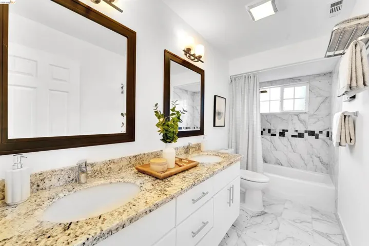 Bathroom featuring a double vanity with granite-style countertops and undermount sinks
