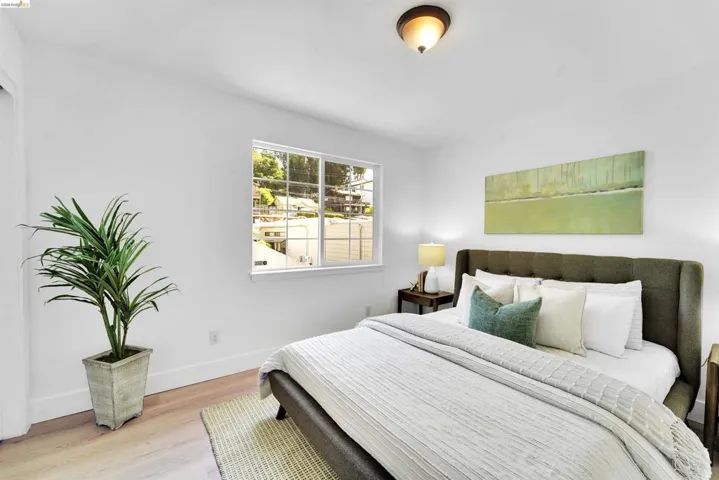 Bedroom featuring light wood-finish flooring, white walls, and a window with white trim