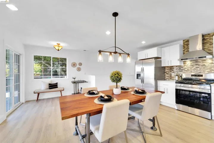 Open-concept kitchen and dining area featuring a wood-finish dining table, recessed lighting, and a modern chandelier