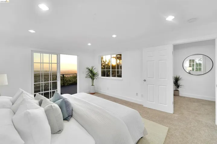 Spacious room featuring a sliding glass door to an outdoor balcony, a large window, recessed lighting, neutral carpet flooring, and a paneled interior door