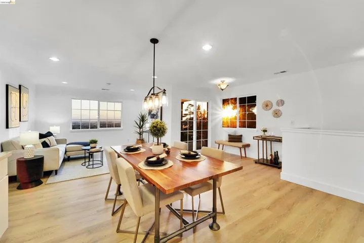Open-concept living and dining area featuring light wood-finish flooring, recessed lighting, and a modern chandelier