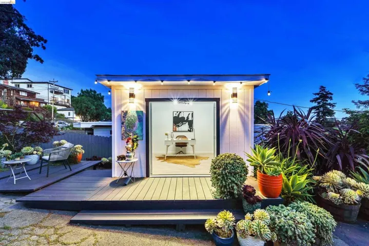 Detached accessory dwelling unit featuring a glass sliding door, exterior wall sconces, and an elevated wood-finish deck