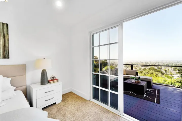 Sliding glass door opening to an expansive outdoor deck with black railing and panoramic distant views
