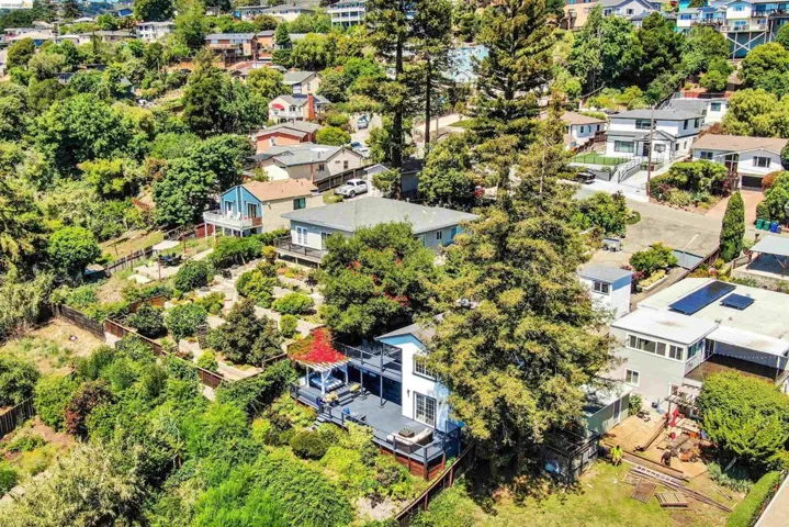 Terraced hillside property featuring multiple decks, mature trees, and landscaping