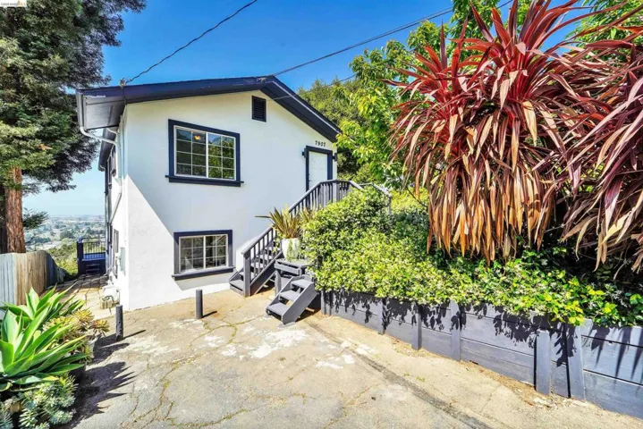 White stucco exterior with dark trim and multi-level landscaping