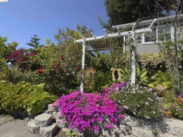 Terraced landscaping featuring vibrant flora, a white pergola, and a stone block retaining wall