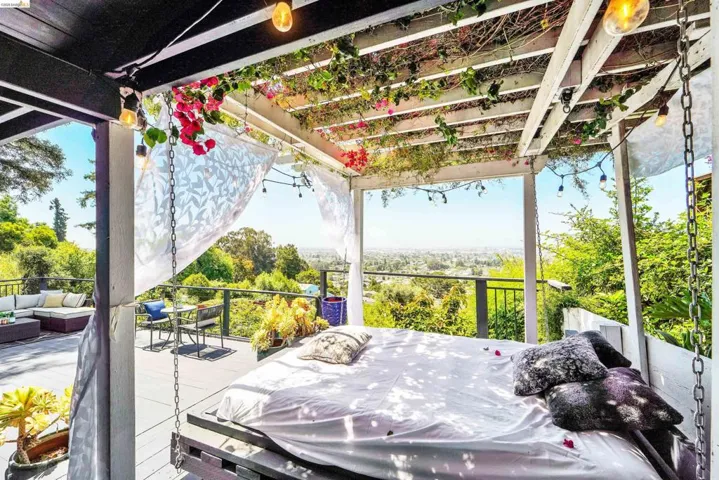 Outdoor deck featuring a pergola with integrated string lighting, lush greenery, and flowering vines