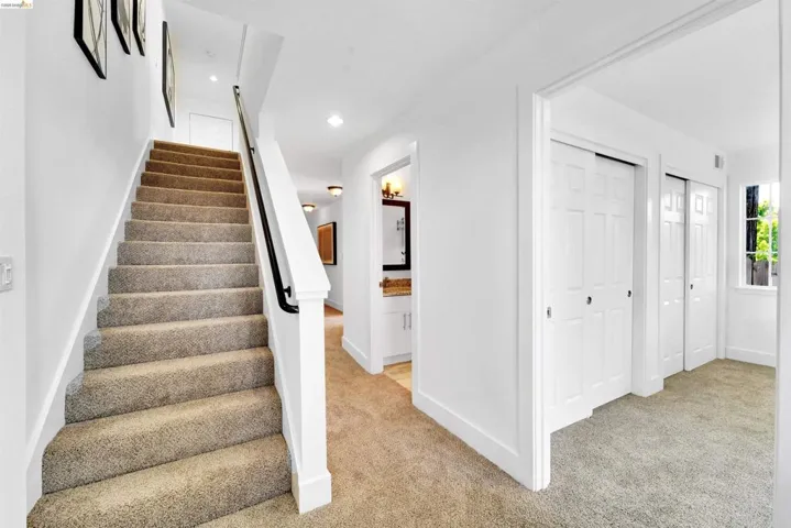 Carpeted staircase with white balusters and a black handrail