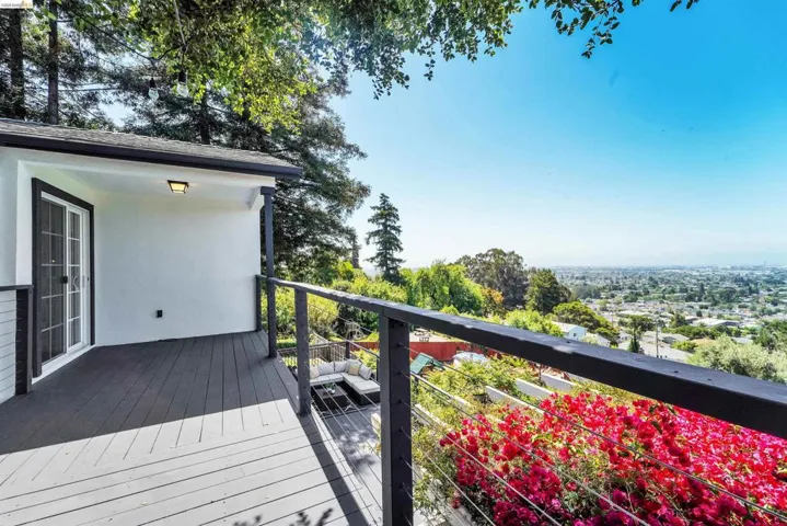 Covered exterior deck with gray wood-finish flooring, white stucco siding, and black trim