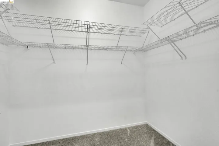 Walk-in closet featuring wire shelving, white walls, and gray carpet flooring