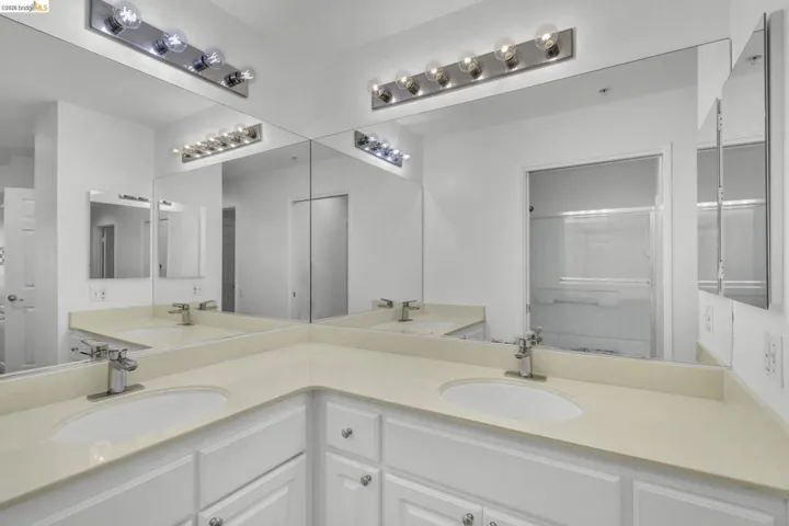 Double vanity featuring white cabinetry, light-toned countertops, undermount sinks, and polished chrome faucets