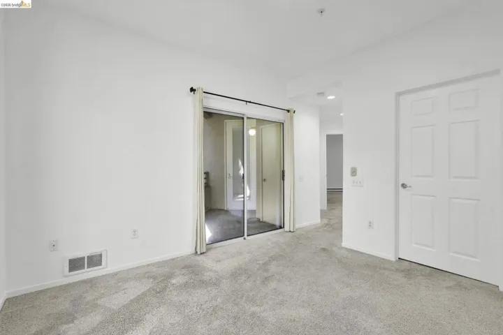 Wall-to-wall carpeting and white walls with a sliding glass door and paneled interior door