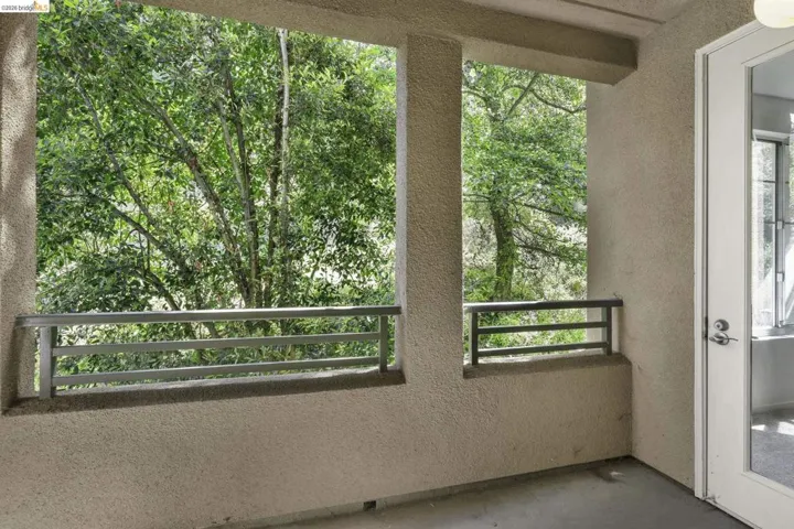 Private balcony featuring textured stucco walls, painted concrete flooring, and metal railings