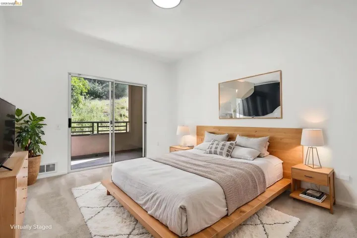 Carpeted bedroom with a sliding glass door leading to a private balcony