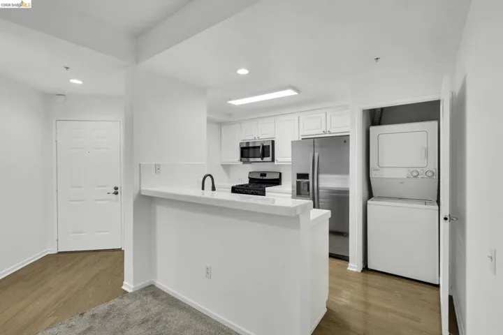 Contemporary kitchen featuring white cabinetry, stainless steel appliances, a white countertop, and a black gooseneck faucet