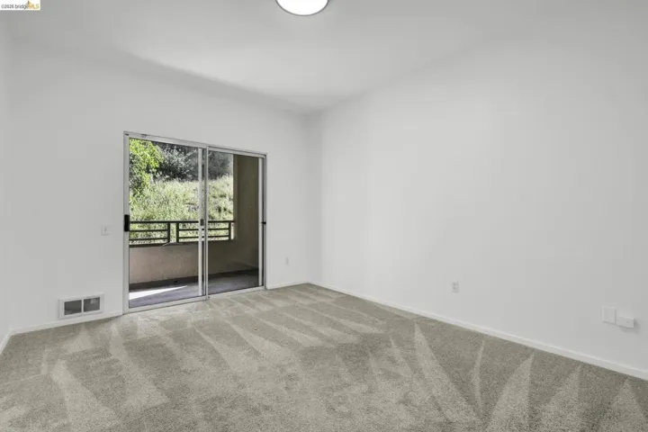 Spacious room with plush carpeting, neutral wall paint, and a modern flush-mount ceiling light