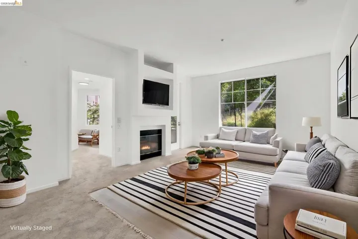 Spacious living area featuring a built-in fireplace, a large window providing ample natural light, soft carpeting, and an integrated media niche