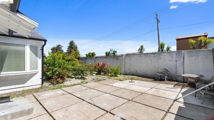 Expansive concrete patio area featuring a white stucco exterior wall with a white-framed window