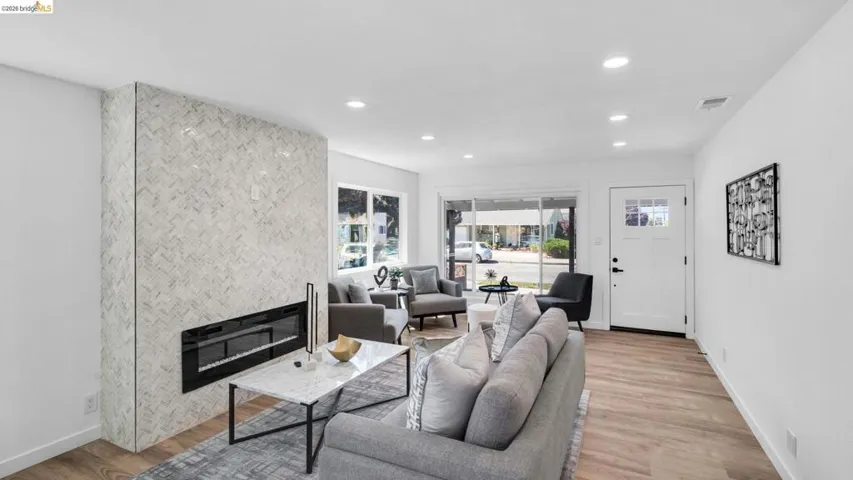 Contemporary living space featuring a floor-to-ceiling fireplace with herringbone tile surround and a linear electric insert