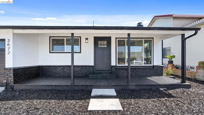 Contemporary exterior featuring a covered porch, dark brick accents, and a dark paneled front door