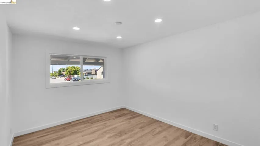 White walls with recessed lighting and wood-finish flooring