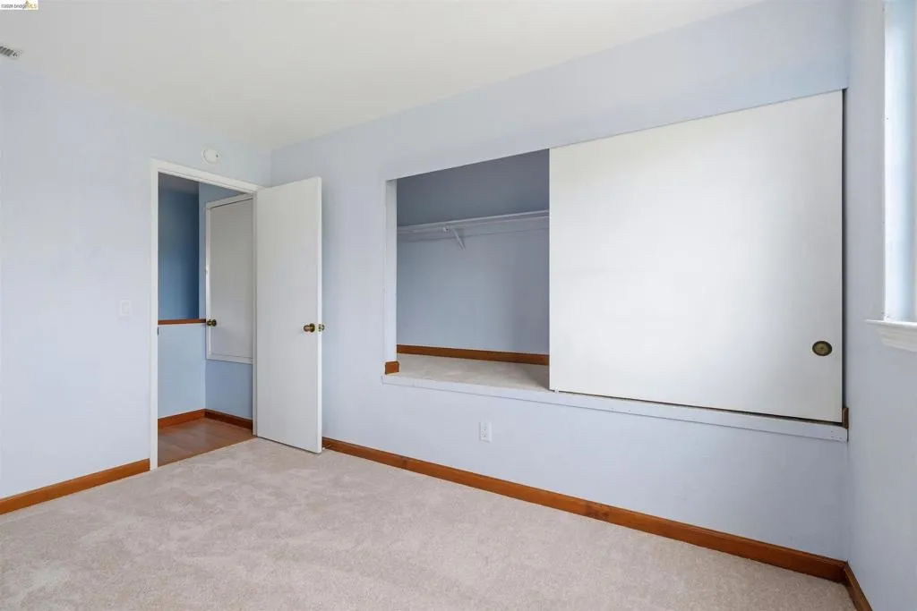 Carpeted room featuring light blue walls, wood baseboards, and a built-in closet with sliding doors