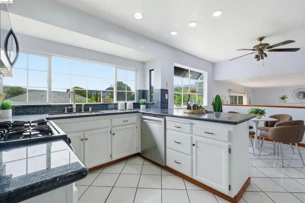 Kitchen featuring white cabinetry, dark stone countertops, tile flooring, and recessed lighting