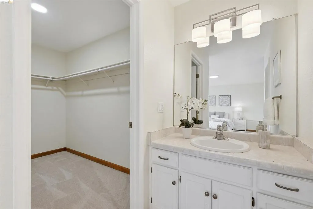 Vanity featuring a white countertop with an integrated sink, white cabinetry with dark hardware, and an oversized mirror