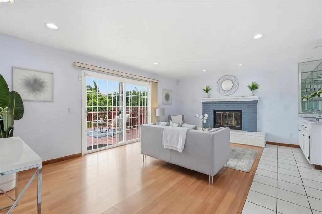 Open concept living area featuring hardwood flooring, a brick fireplace, recessed lighting, and sliding glass doors with direct patio access
