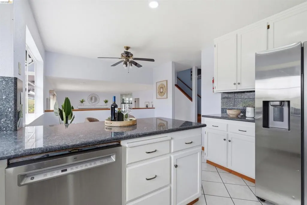 Kitchen featuring dark stone countertops, white cabinetry with dark hardware, stainless steel appliances, and tile flooring