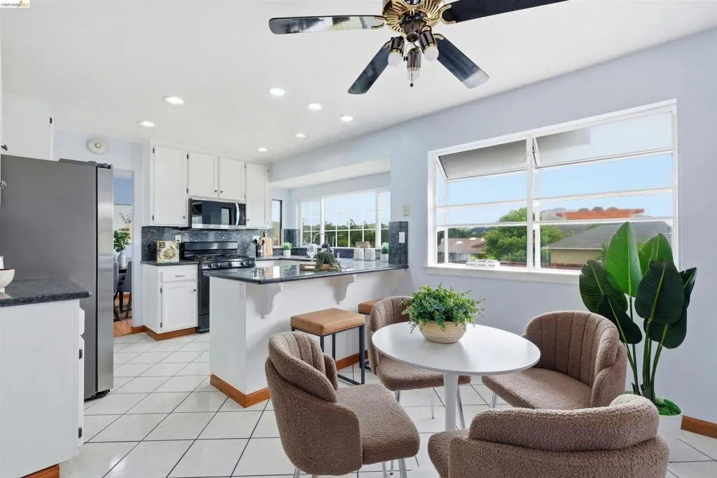 Kitchen featuring white cabinetry, dark countertops, a built-in microwave, tiled flooring, and a ceiling fan with integrated lighting