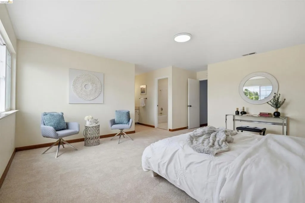 Carpeted bedroom featuring neutral wall tones, a large window, recessed lighting, and a doorway to an adjacent bathroom