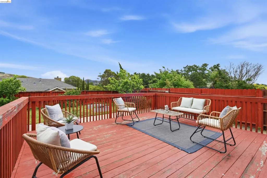 Spacious red-stained wood deck featuring a high perimeter fence