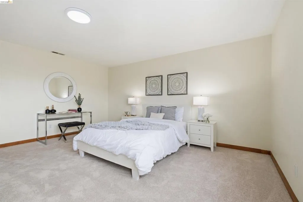 Carpeted bedroom featuring a circular ceiling light fixture, neutral wall color, and wood baseboards
