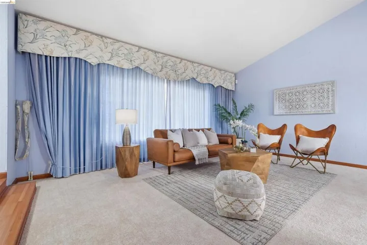 Expansive living area featuring a vaulted ceiling and wall-to-wall carpeting