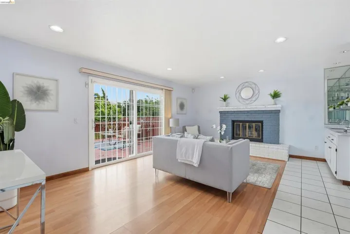 Open concept living area featuring hardwood flooring, a brick fireplace, recessed lighting, and sliding glass doors with direct patio access