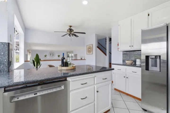 Kitchen featuring dark stone countertops, white cabinetry with dark hardware, stainless steel appliances, and tile flooring