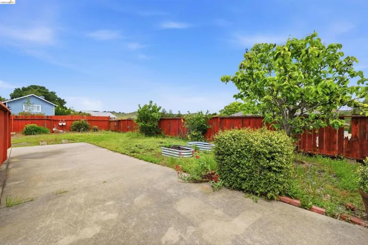 Expansive concrete patio area with a wooden privacy fence