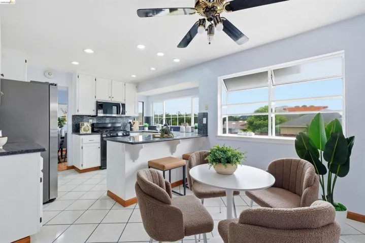 Kitchen featuring white cabinetry, dark countertops, a built-in microwave, tiled flooring, and a ceiling fan with integrated lighting