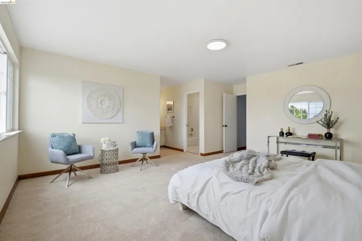 Carpeted bedroom featuring neutral wall tones, a large window, recessed lighting, and a doorway to an adjacent bathroom