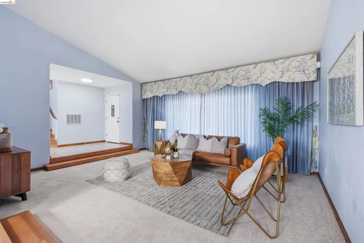 Spacious living area featuring a vaulted ceiling and light blue wall tones