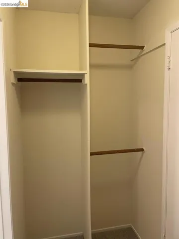 walk in closet featuring dark carpet