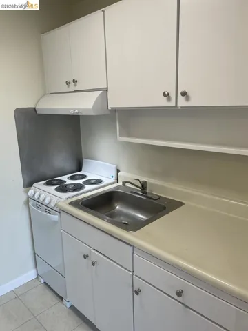 kitchen with white cabinets, white electric range oven, light countertops, and light tile patterned flooring