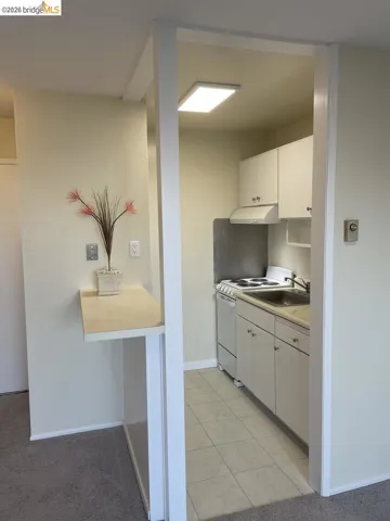 kitchen with light countertops, white cabinets, white electric range oven, light tile patterned flooring, and light colored carpet