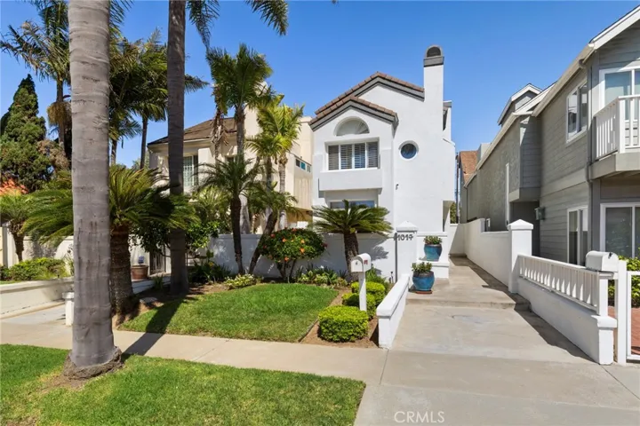 Inviting curb appeal highlighted by lush tropical landscaping and coastal plantings