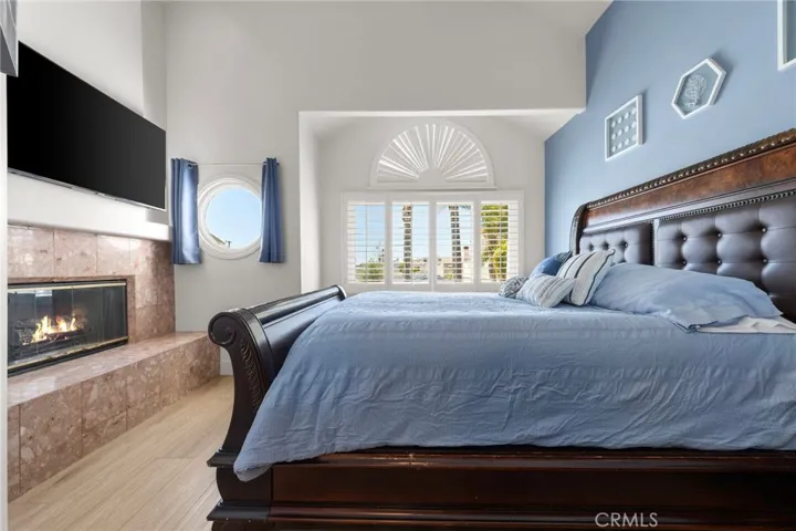Serene master retreat with high ceilings, a fireplace, and an abundance of natural light creating a bright, inviting escape