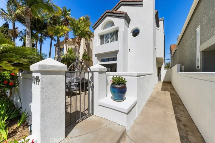 Entry view framed by vibrant tropical landscaping, looking into the front courtyard