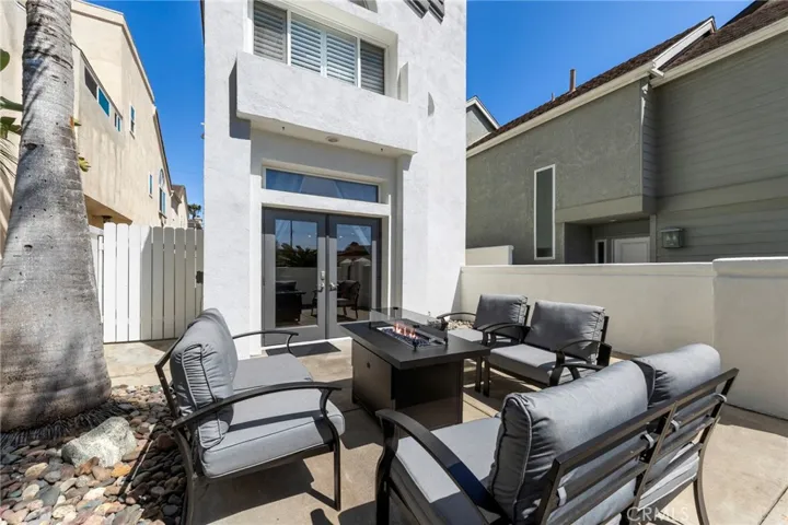 Front courtyard patio with firepit seating flowing seamlessly into the den and kitchen through French doors