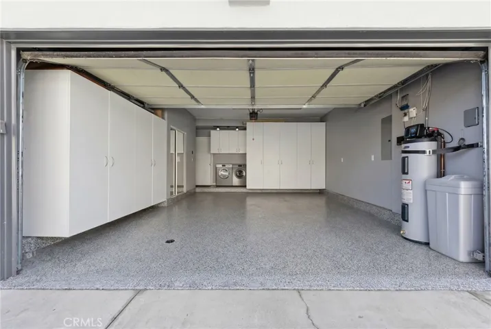 Well-appointed attached garage with laundry, built-in storage, and water heater
